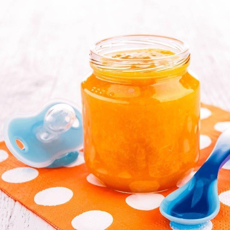 Foto com pote de papinha, chupeta e uma colher